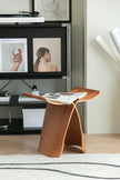 Wooden stool side table with magazines in a living room setting
