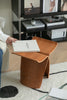 Women holding a book next to a modern wooden stool in a living room setting.