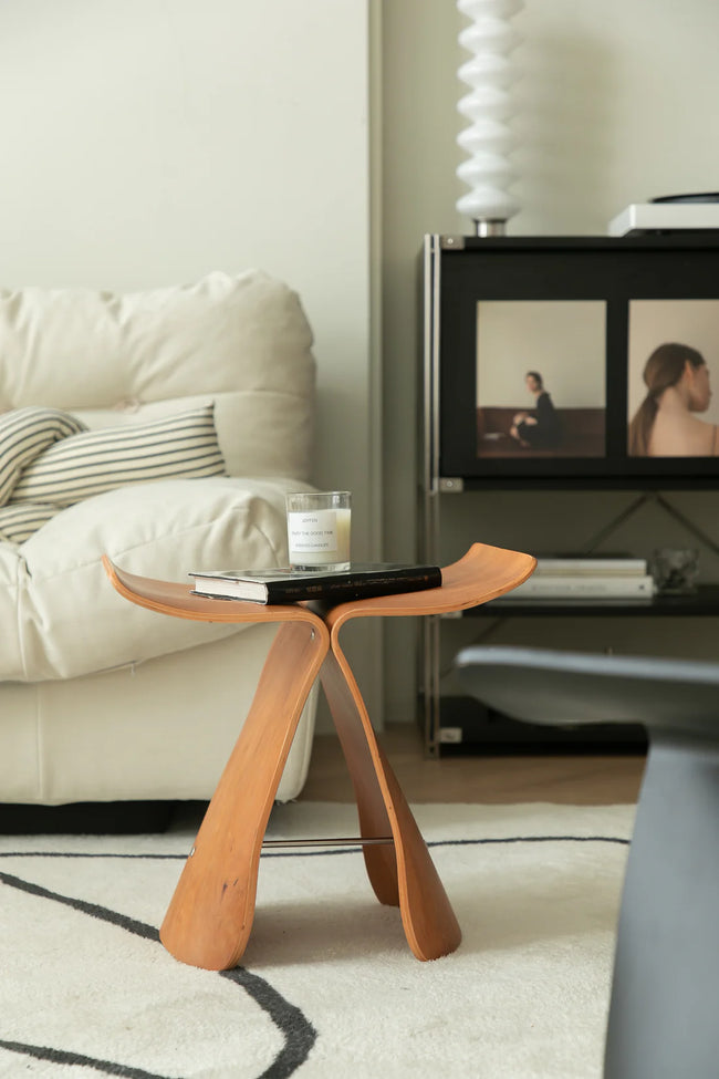 Wooden stool in a living room setting with a sofa and television.