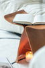 Wooden stool with an open book and a lit candle on a bed