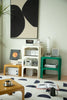 Modern living room with a white square coffee table, green small side table, and abstract art on the wall.