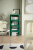 Green modular coffee table with books and decor in a room with a white wall and patterned rug.