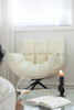 White leather swivel comfy chair in a room with a candle and book on a table.