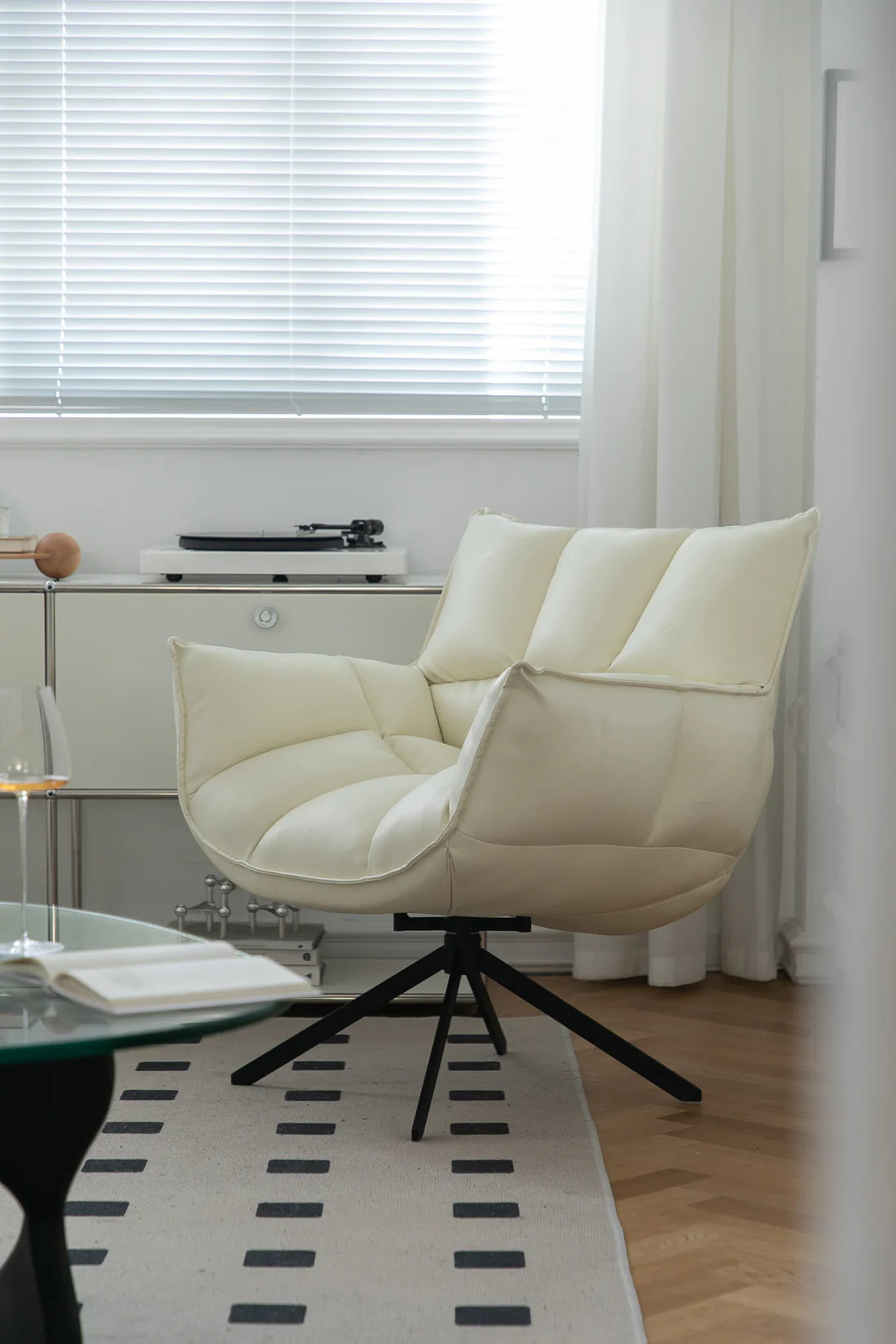 Beige leather swivel armchair in a room with a window and rug