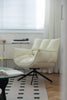 Beige leather swivel armchair in a room with a window and rug