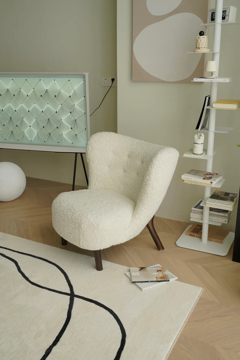 Modern living room with a white sofa chair, TV, and decorative items.
