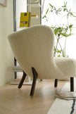 Beige sofa reclining chair in a modern interior setting with a plant and magazine in the background.