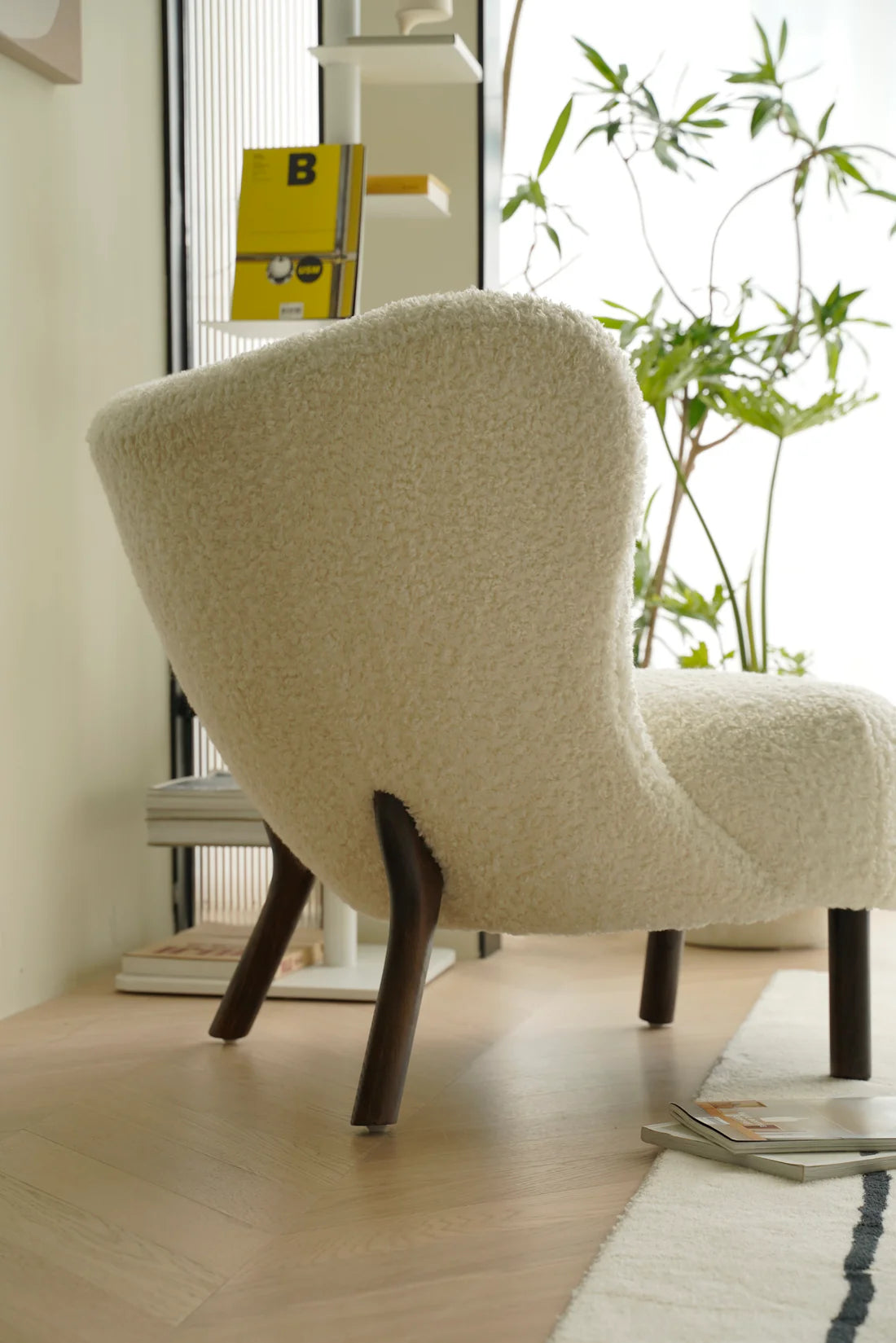 Beige sofa reclining chair in a modern interior setting with a plant and magazine in the background.