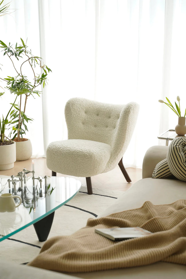 Modern living room with a beige living room chair, glass coffee table, and decorative plants.