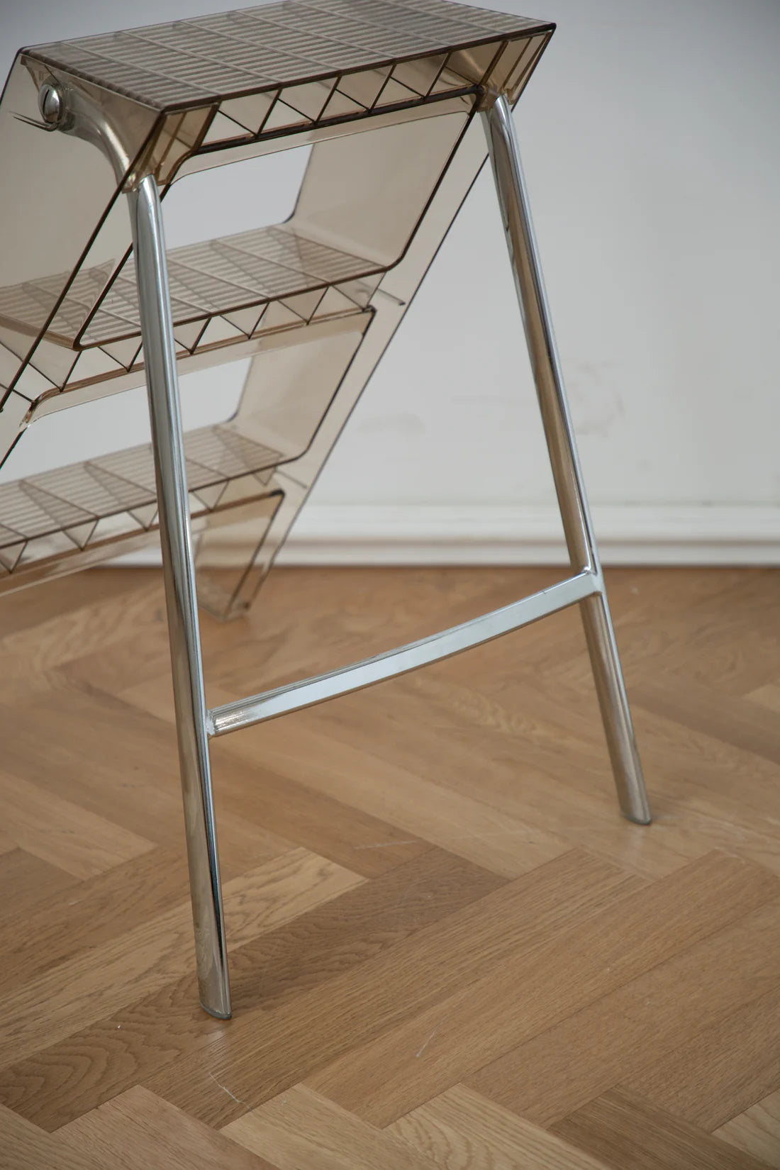 Metal & abs ladder rack with transparent backrest on a wooden floor