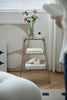 Decorative three-tiered ladder shelf with books and a vase of flowers in a room setting.