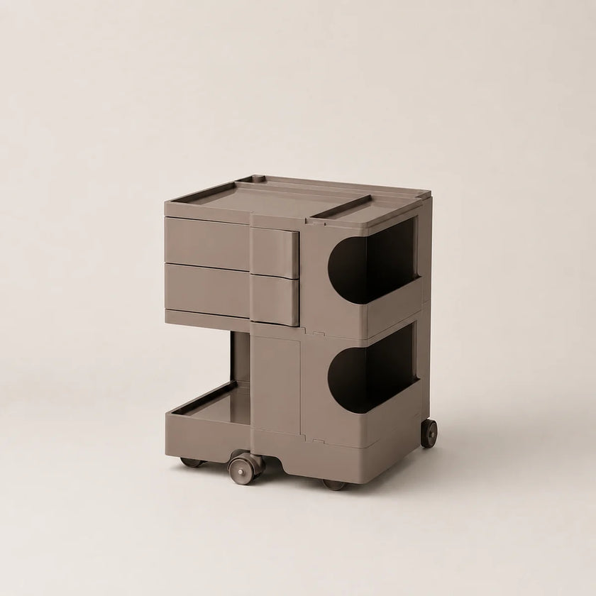 A modern, minimalist two-tier rolling storage cart in a warm brown color, featuring a top drawer unit, open shelves with curved cutouts, and a bottom tray on wheels, set against a solid light beige background.