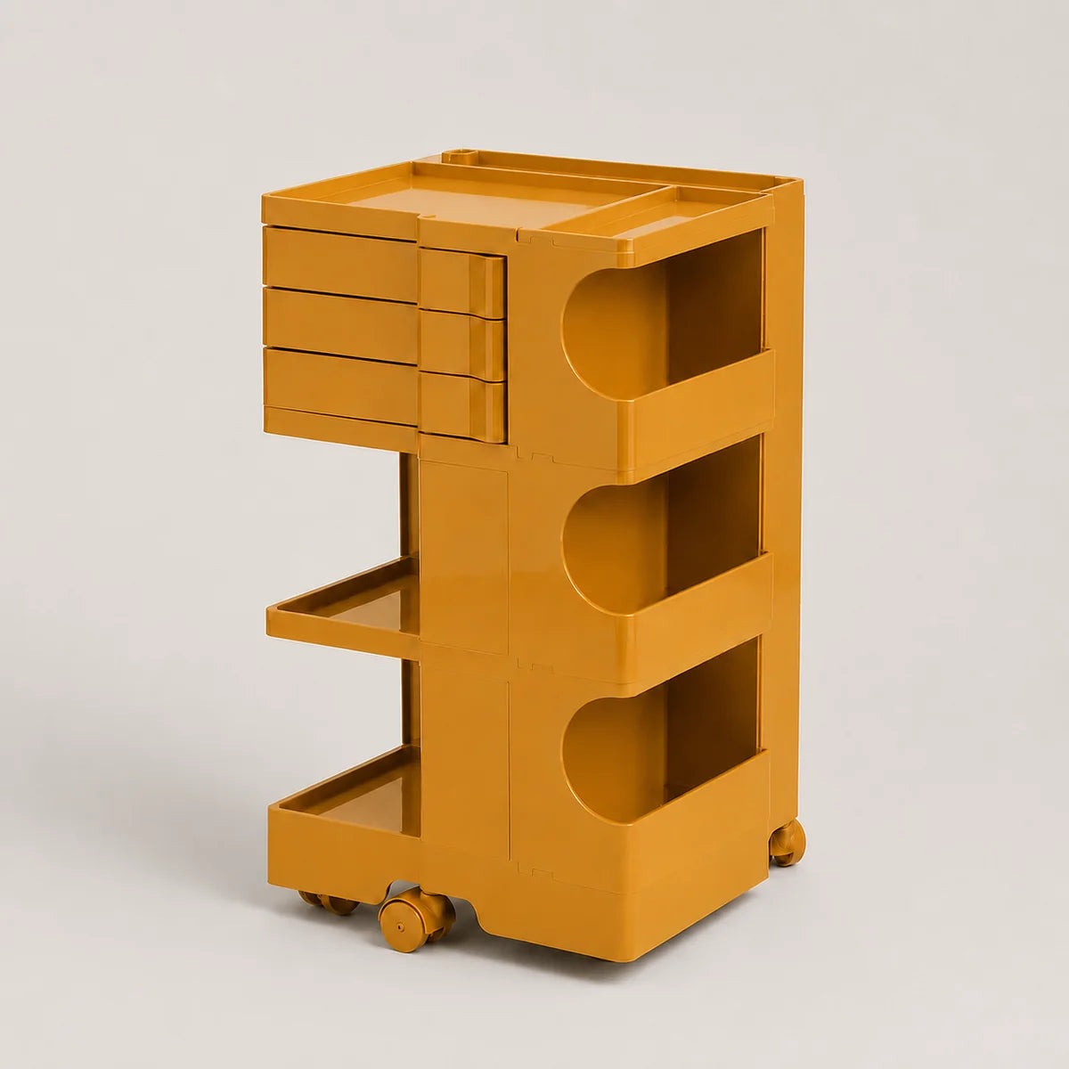 A bright yellow-orange rolling storage cart with a top tray, three drawers on the upper left, three open shelves on the right, and caster wheels, photographed on a light gray studio background.