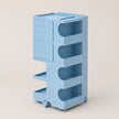 A light blue plastic storage organizer with drawers, open shelves, and caster wheels, shown on a plain beige studio background.
