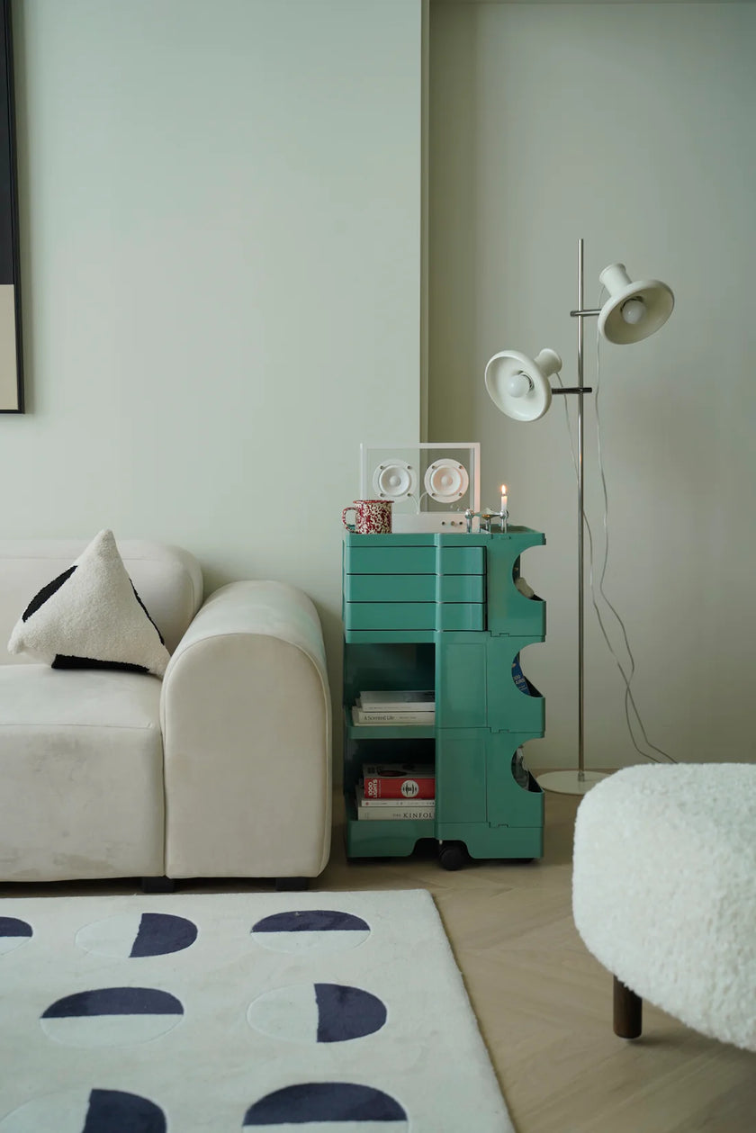 Modern living room with a white sofa, utility cart with wheels or teal side table, and decorative items.