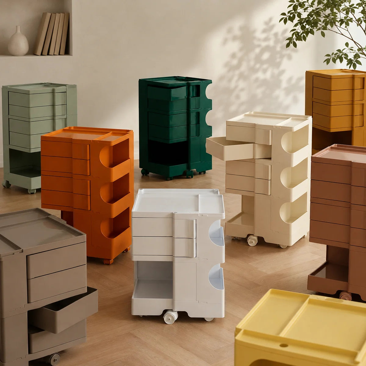 Nine rolling storage drawers in different colors are arranged in a modern interior room. The drawers have a stacked, rectangular design with three drawers on the left and two on the right, all on black caster wheels.