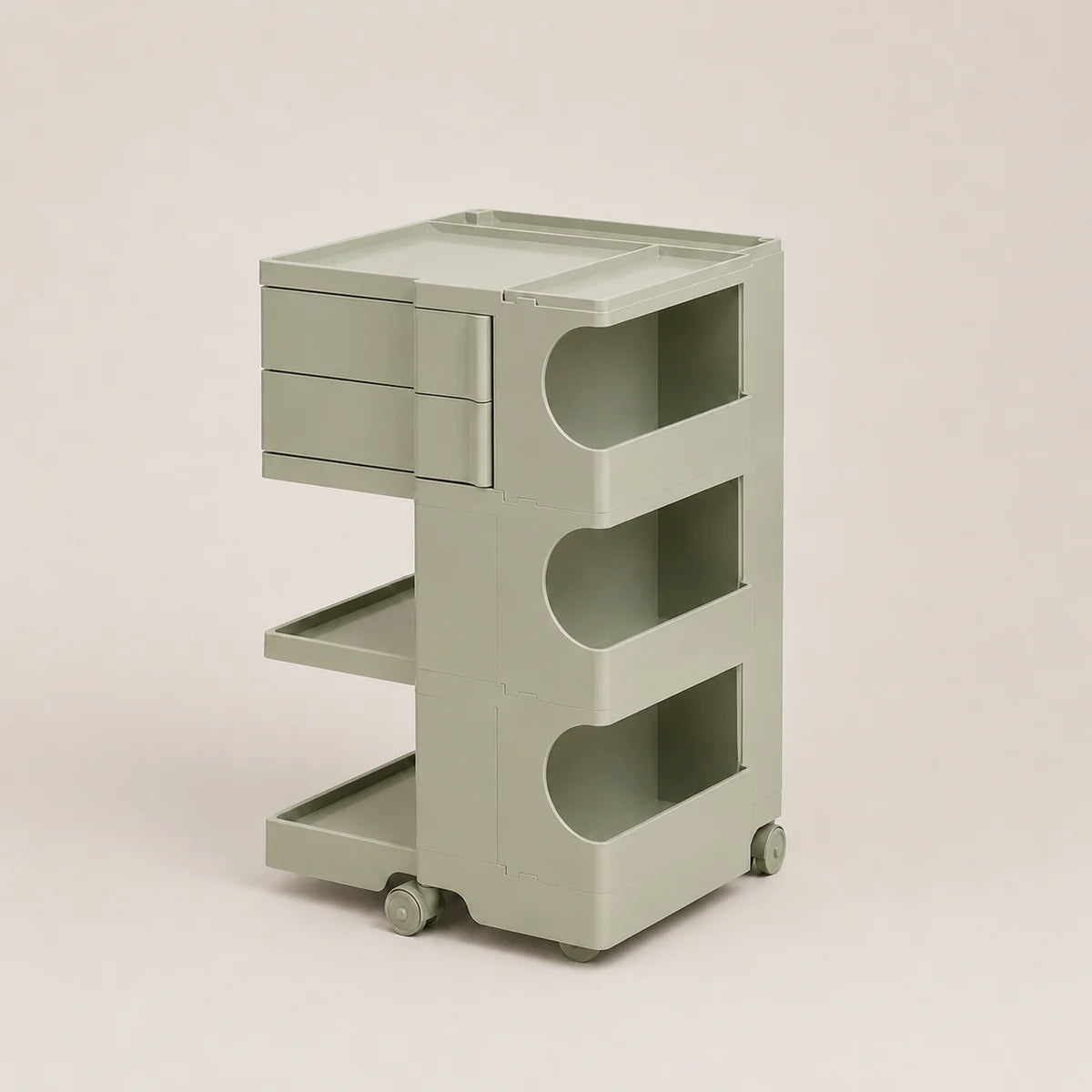 A light matcha green plastic rolling organizer cart with two drawers on the top left, three open shelves with curved cutouts, and small caster wheels, shown on a plain beige studio background.
