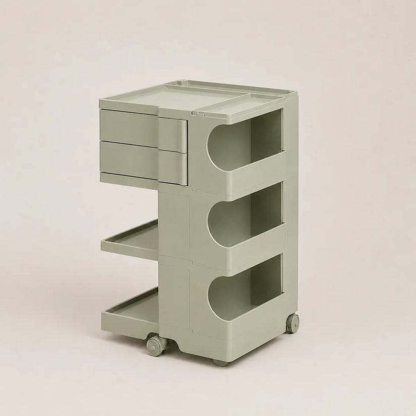A light matcha green plastic rolling organizer cart with two drawers on the top left, three open shelves with curved cutouts, and small caster wheels, shown on a plain beige studio background.