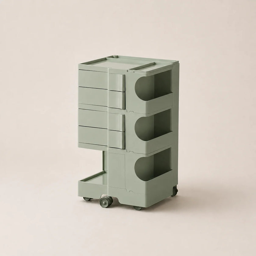 A modern three-tier rolling storage cart in a muted sage green color, featuring drawers on the top two levels and open shelves on the bottom, set against a solid light beige background.