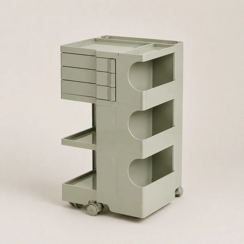 A light sage green plastic rolling organizer cart with a top drawer unit, three open shelves, and caster wheels, shown against a solid light beige background.