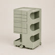 A light sage green storage cart with multiple drawers, open shelves, and a top tray, shown on a plain light beige background.