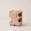 A minimalist beige rolling storage cabinet with two drawers on the top and two open shelves on the bottom, shown on a plain warm beige background.