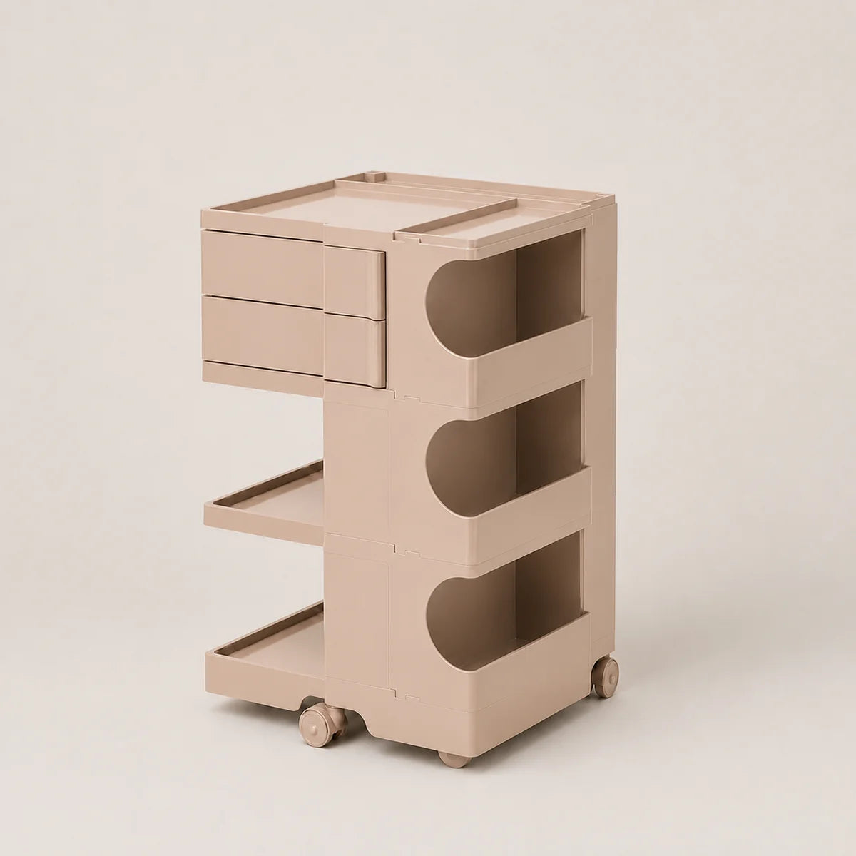 A minimalist mutedpink rolling storage cart with two drawers on the left, three open shelves on the right, and small caster wheels at the base, photographed on a clean light beige studio background.