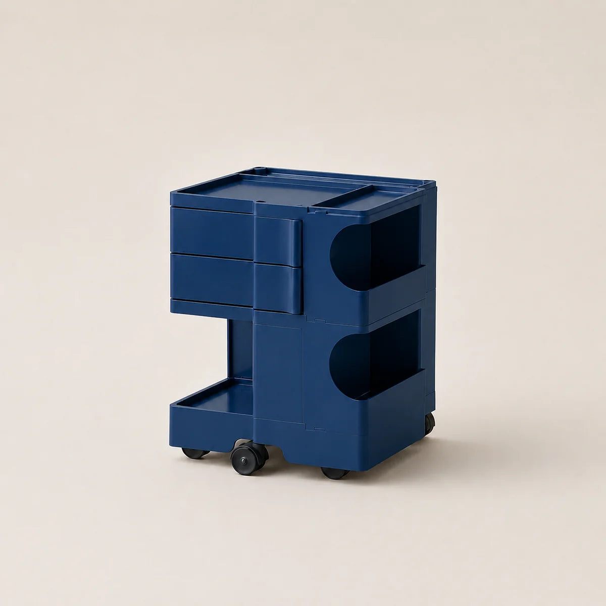 A steel blue ABS plastic storage cart with two drawers, open shelves, and small black wheels, photographed on a clean, solid, warm off-white background.