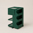 A vintage green ABS plastic rolling storage cart with two drawers, three open shelves, and wheels, shown on a plain beige background.