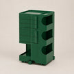 A dark green ABS storage cart with multiple drawers, open shelves, and caster wheels, photographed on a neutral light beige background.