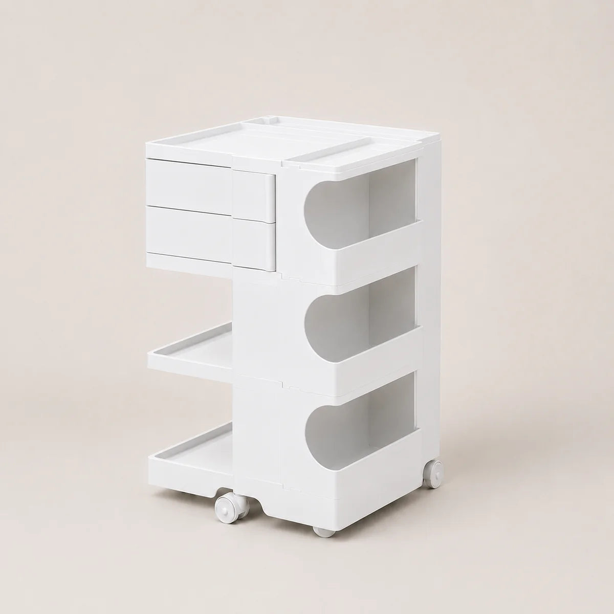 A white three-tier rolling storage cart with drawers on the top left, open shelves on the right, and caster wheels at the base, photographed against a solid light beige background.