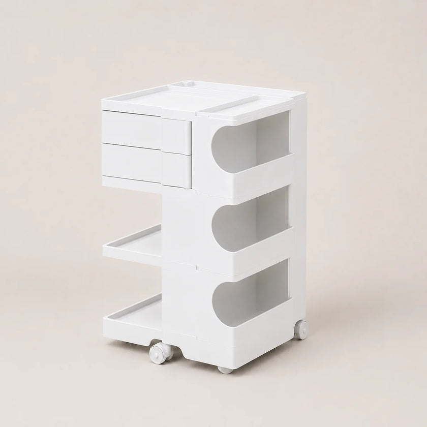 A white three-tier rolling storage cart with drawers on the top left, open shelves on the right, and caster wheels at the base, photographed against a solid light beige background.