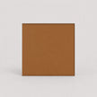 A square tan-brown textured panel or tile with a thin dark border, centered on a light gray background.