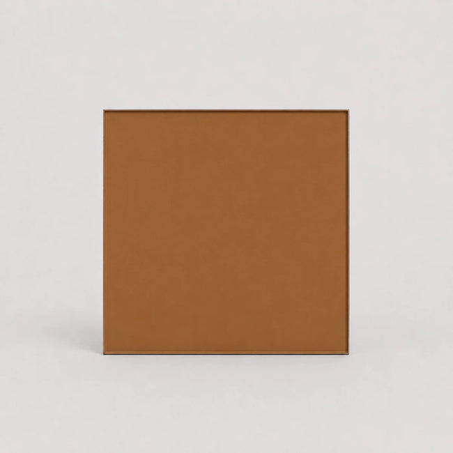 A square tan-brown textured panel or tile with a thin dark border, centered on a light gray background.