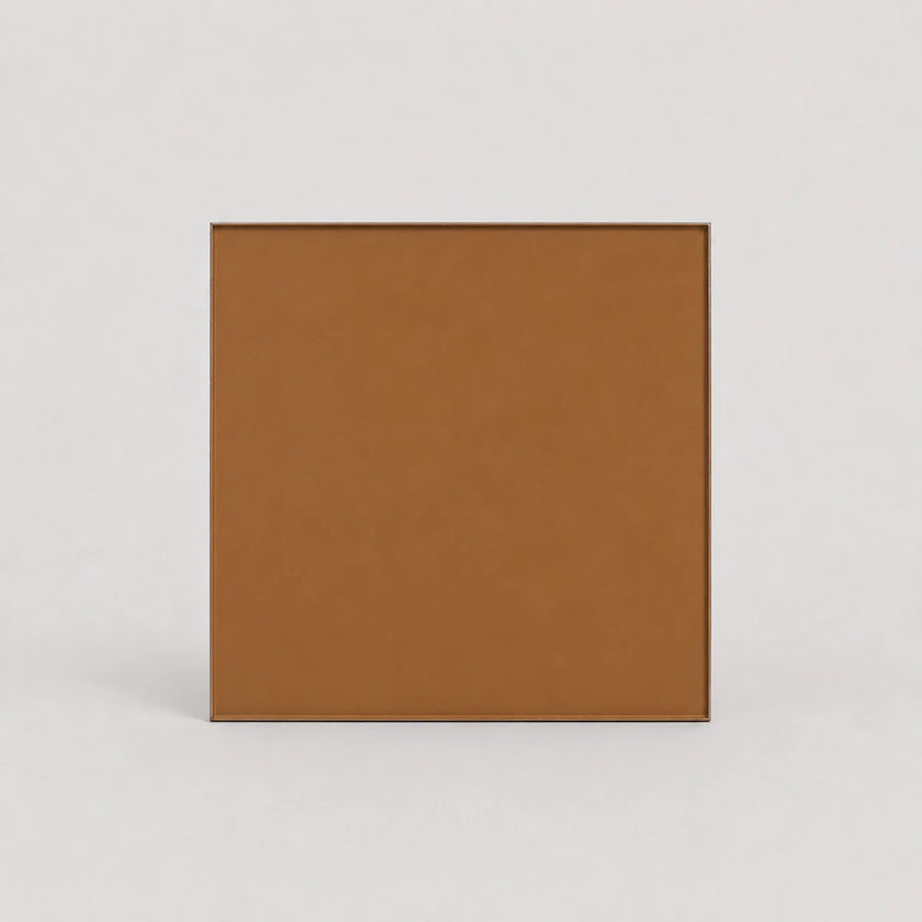 A square tan-brown textured panel or tile with a thin dark border, centered on a light gray background.