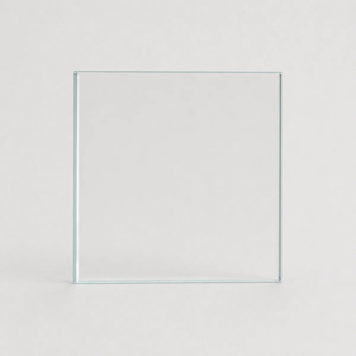 A clear square glass tile or panel standing upright against a light gray background.