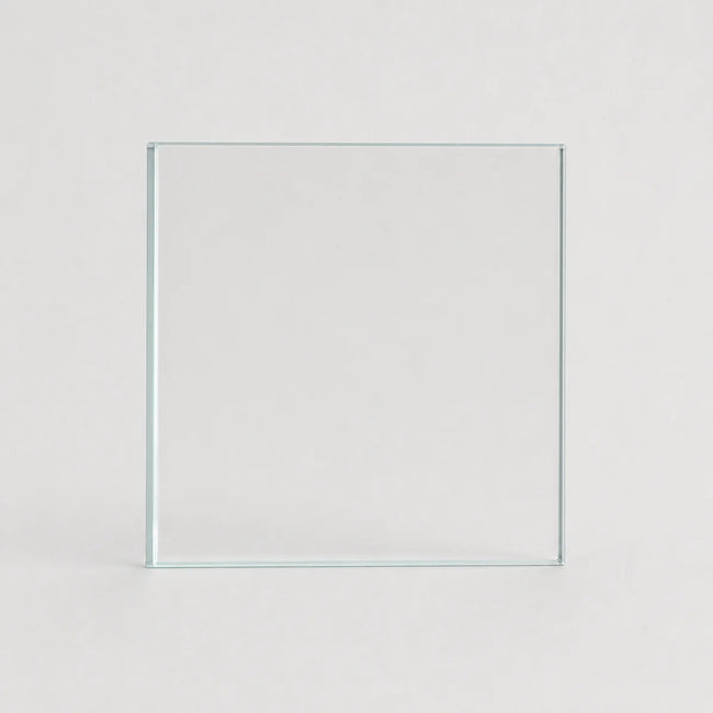 A clear square glass tile or panel standing upright against a light gray background.