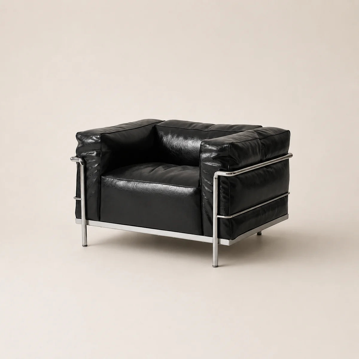 A black leather armchair with a chrome metal frame, photographed against a solid light beige background.