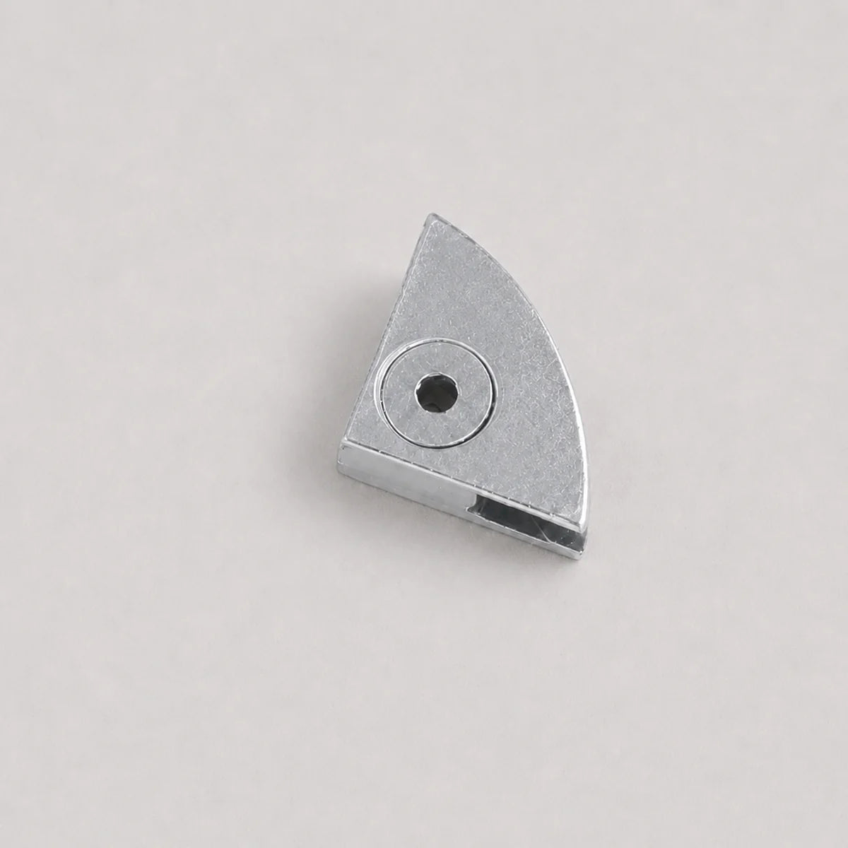 A small metallic silver metal component with a triangular shape and a circular hole, photographed on a plain light gray background.