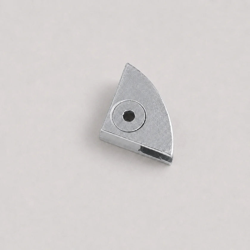 A small metallic silver metal component with a triangular shape and a circular hole, photographed on a plain light gray background.
