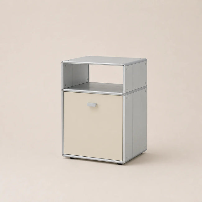 A modern modular storage cabinet with a light gray metal frame and a cream-colored front door, set against a solid beige background.