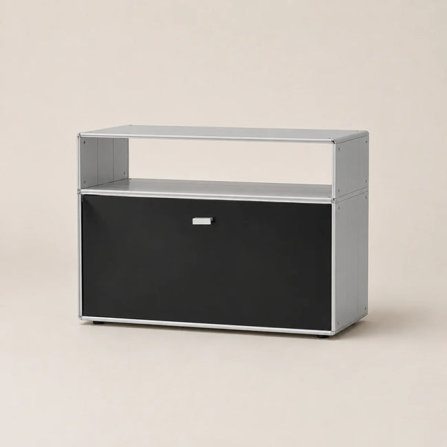 A modern two-tier storage cabinet with a black front door and open upper shelf, finished in a light gray color with a small silver handle, set against a solid beige background.