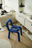 Blue vanity chair in a modern living room setting with a white sofa and decorative items.