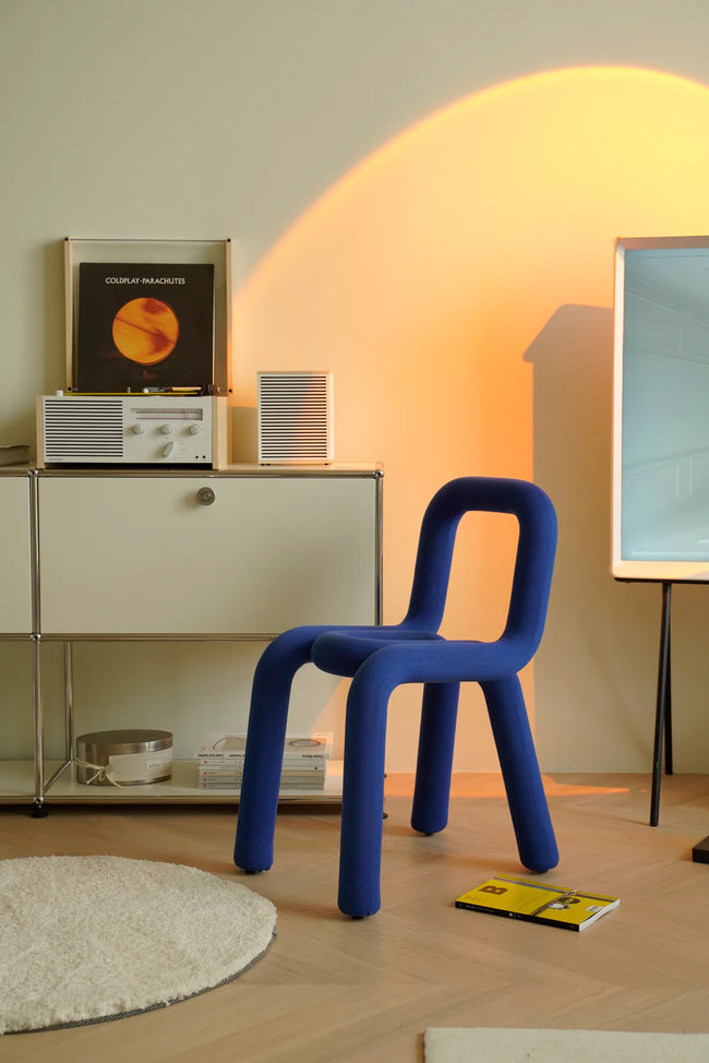 Blue living room chair in a room with a vintage radio and records on a shelf.