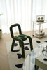 Modern green vanity chair in a room with a glass table and decorative items.
