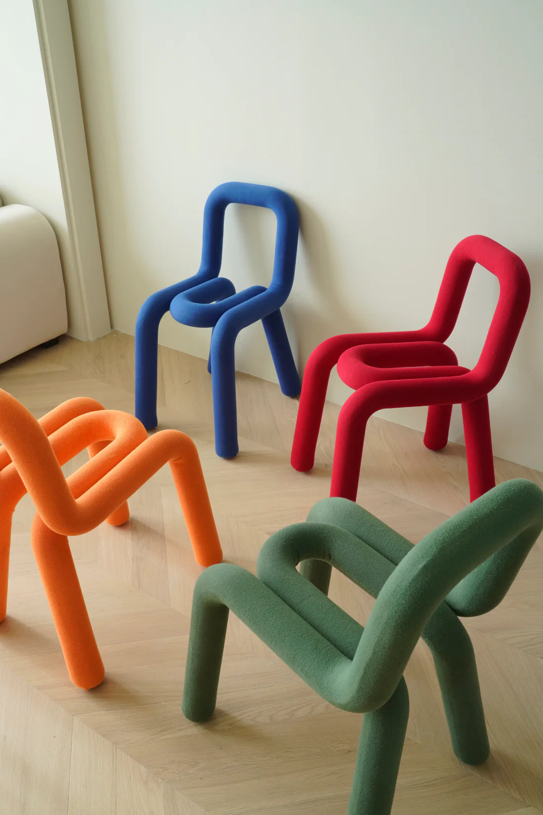 Colorful children's chairs in blue, red, orange, and green on a light wooden floor.