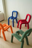 Colorful children's chairs in blue, red, orange, and green on a light wooden floor.