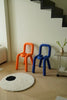 Two colorful kids chairs, one orange and one blue, in a room with a white rug and a small table with plants.