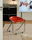 A stack of red folding chairs with chrome metal frames is shown in a home interior setting, with a person's hand reaching to adjust the top chair.