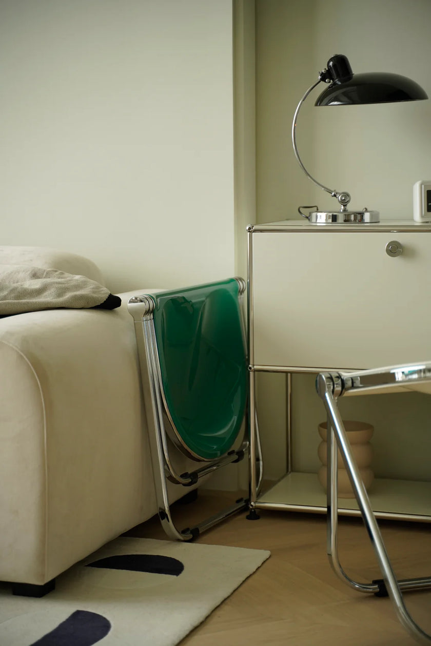 Modern living room with a white sofa, green folding stool, and a black lamp.